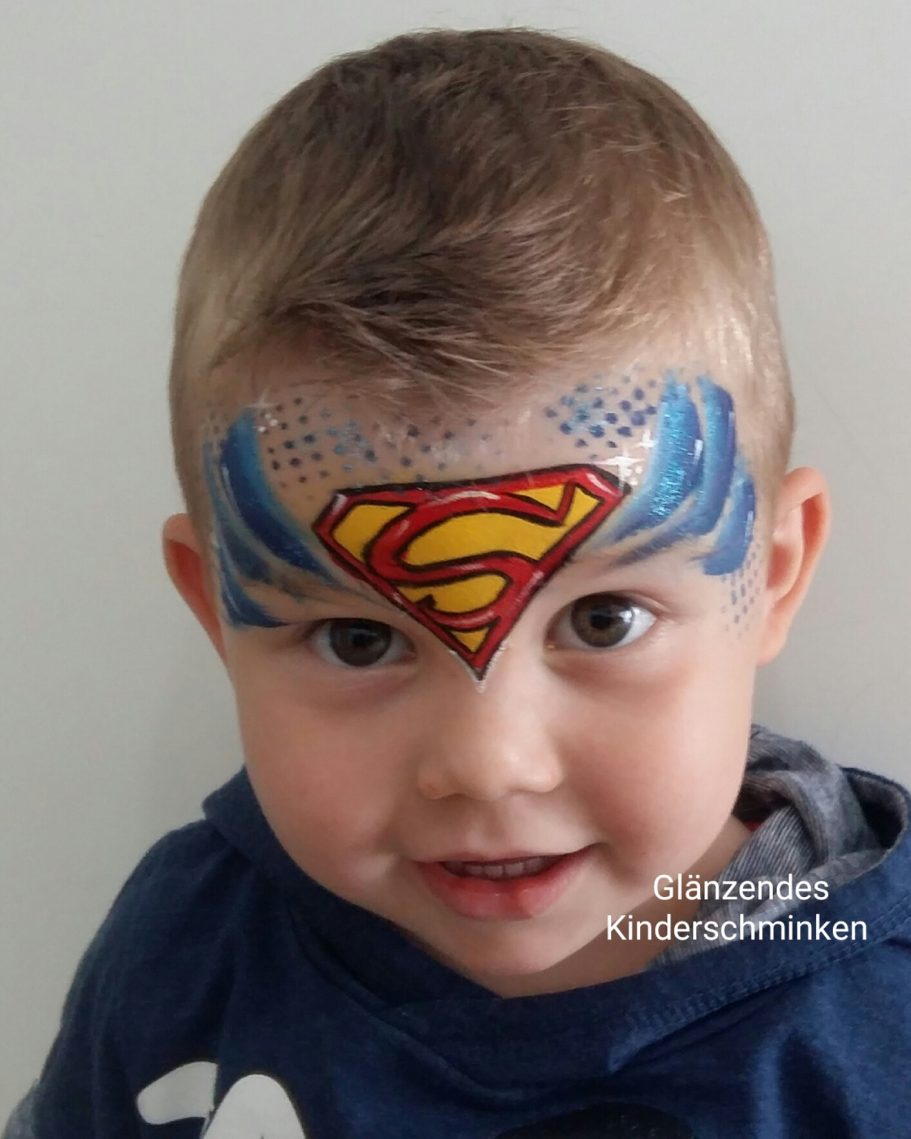 Ein kleiner Junge mit Superman-Gesichtsbemalung auf der Stirn.